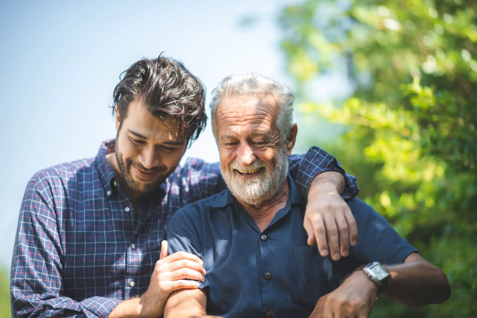 senior father and adult son are hugging together at home